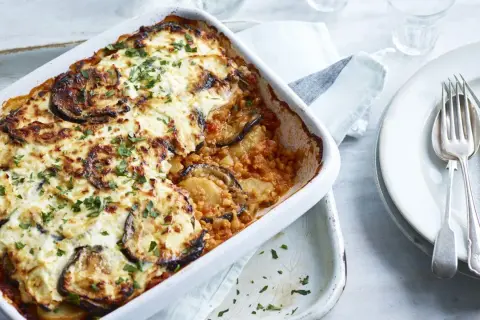 Un plat de moussaka végétarienne gratinée, garni d'aubergines et de persil frais, prêt à être dégusté.