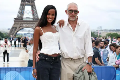 Narah Baptista sorride accanto a Vincent Cassel con la Torre Eiffel e gli anelli olimpici sullo sfondo.