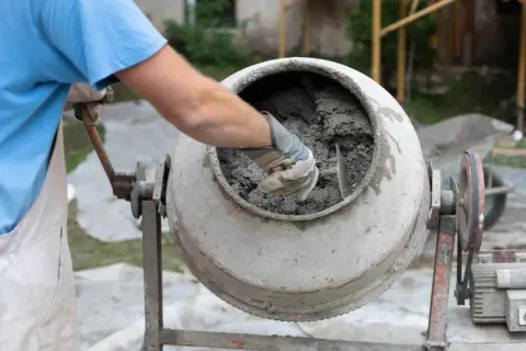 Robotnik miesza beton w betoniarce. Zastanawiasz się, ile betonu z tony cementu? To zależy od proporcji!