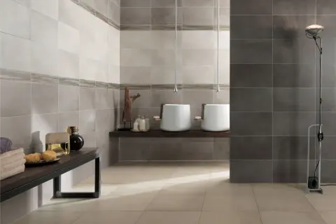 Bagno moderno con lavabi sospesi e piastrelle a diverse altezze, che creano un effetto visivo dinamico.