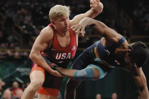 Två brottare i intensiv kamp. En bär USA:s färger, den andra en mörkblå dräkt. Spänningen är påtaglig i denna wrestling sverige-match.