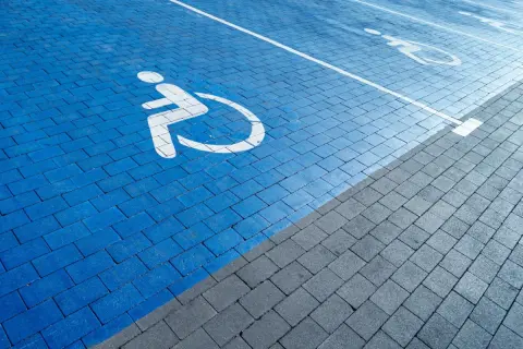 Niebieski parking z symbolem wózka inwalidzkiego. Orzeczenie o niepełnosprawności można uzyskać na wiele chorób, które ograniczają sprawność.