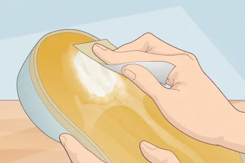 Préparation d'une semelle de chaussure pour la recoller sans colle. Une main frotte la surface avec un papier abrasif.