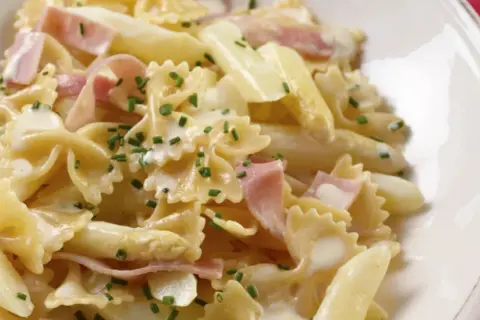 Leckere Spargel Pasta mit Schinken in cremiger Sauce, garniert mit Schnittlauch.