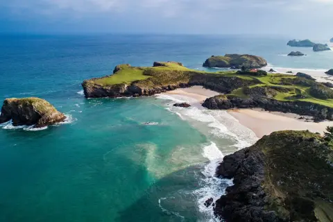 Impresionante vista aérea de la ruta costa Asturias en coche. Playas doradas, acantilados verdes y el mar turquesa crean un paisaje idílico.
