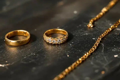 Anillos de oro 375, que significa 9 quilates, y una cadena dorada sobre fondo oscuro.
