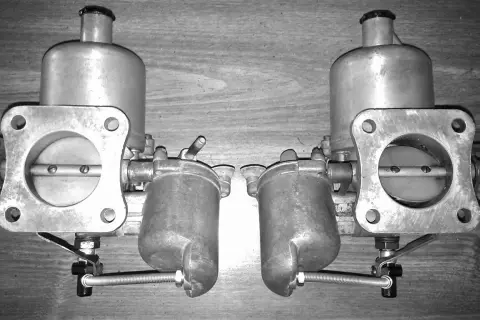 Dos carburadores gemelos, mostrando sus partes metálicas y el mecanismo de mariposa.