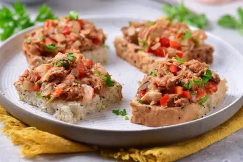 Chrupiące grzanki z makrelą w pomidorach, posypane natką pietruszki. Idealna przekąska na szybki lunch.