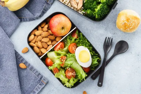 Zdrowe lunchboxy do pracy przepisy: sałatka z jajkiem, pomidorkami i sałatą, jabłko, migdały i ryż z brokułami.