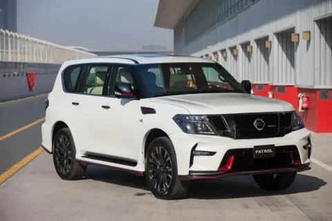 Biały Nissan Patrol Nismo z czerwonymi akcentami stoi na torze wyścigowym.
