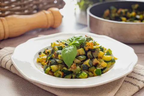 Herzhafte zucchini pfanne, frisch zubereitet und mit Basilikum garniert, serviert auf einem weißen Teller.