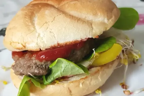 Pyszny burger z soczystym kotletem, sałatą, keczupem i żółtym serem. Idealny przykład, jak usmażyć burgera na patelni.