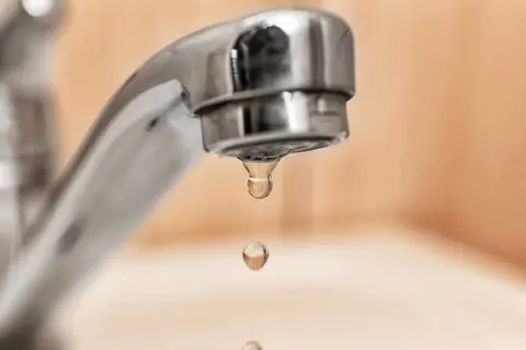 Gocce d'acqua cadono da un rubinetto cromato. Speriamo che non esca acqua dai rubinetti di casa, altrimenti sarebbe un problema!