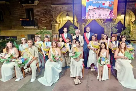 Jóvenes y adultos celebran las fiestas de Monzón, luciendo trajes elegantes y portando ramos de flores.