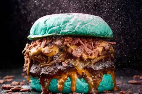 Una hamburguesa gigante con pan azul, carne jugosa, queso derretido y crujiente tocino, perfecta para un festival hamburguesa.