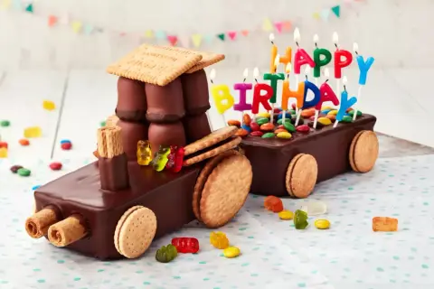 Schokoladen-Traktor-Torte, die man leicht selber machen kann, mit bunten Kerzen und Gummibärchen verziert.