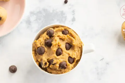 Leckeres Protein Cookie Dough Rezept in einer Tasse, mit Schokostückchen und auf einem Löffel mit Streuseln.