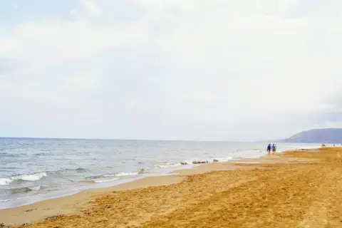 Spokojne morze i piaszczysta plaża na Zakynthos w maju. Kilka osób spaceruje brzegiem, ciesząc się łagodnym słońcem i ciszą.