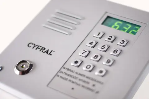 Panel domofonu Cyfral z klawiaturą numeryczną i wyświetlaczem. Instrukcja podpowiada, jak ściszyć domofon, wybierając numer mieszkania i potwierdzając go.