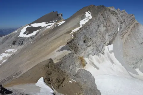 Vue spectaculaire d'une crête rocheuse et enneigée lors d'une barrhorn randonnée. Le ciel bleu azur domine.