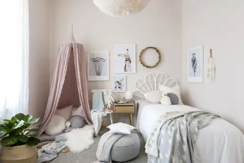 A dreamy baby girls bedroom with a pink canopy, cloud-patterned blanket, and whimsical art.