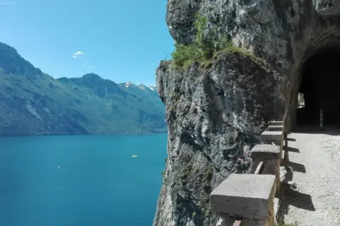 Sentiero panoramico per trekking a Riva del Garda, con vista sul lago e un tunnel scavato nella roccia.