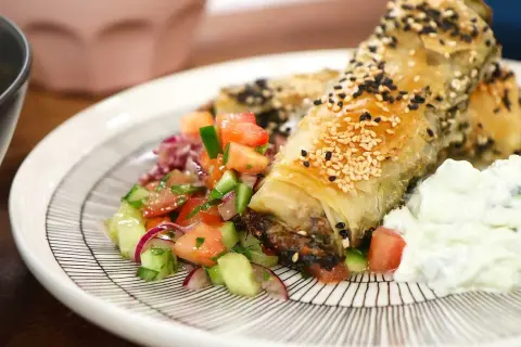 Krispiga filodegsrullar med sesamfrön, serverade med en fräsch tomatsallad och yoghurt. Ett utsökt burek recept!