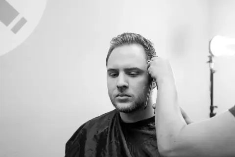 Un uomo con barba e basette viene tagliato. Diverse tipi di basette sono possibili, ma queste sono in fase di definizione.