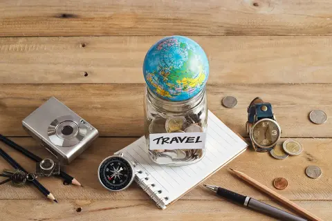 Bocal rempli de pièces avec un globe, un appareil photo, une boussole et un carnet, prêt pour le backpacking en Europe.