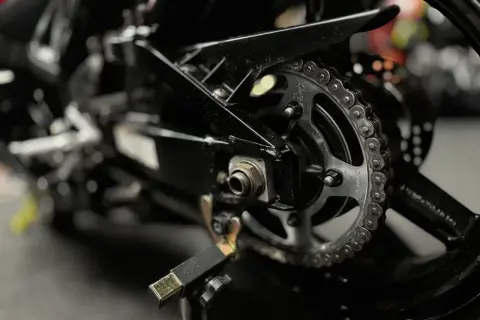Zbliżenie na zębatkę i łańcuch motocyklowy. Dowiedz się, czym czyścić łańcuch motocyklowy, by był jak nowy.