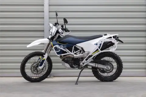 Motocykl enduro Husqvarna 701 z bagażnikiem i osłonami, biało-niebieski.