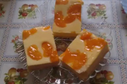 Drei Stücke faule weiber kuchen mit Mandarinen auf einem Tisch mit Blumenmuster.