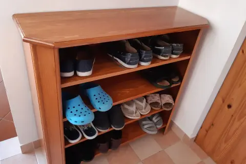 Scarpiera fai da te in legno, con scarpe da ginnastica, infradito e zoccoli blu.