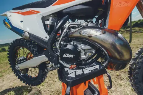 Potężny silnik dwusuwowy KTM z charakterystycznym wydechem FMF, gotowy do jazdy po bezdrożach.