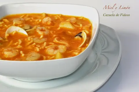 Cazuela de fideos con gambas y mejillones en un cuenco blanco.
