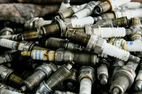 Stos zużytych świec zapłonowych, niektóre z oznaczeniem p0302, gotowe do recyklingu.