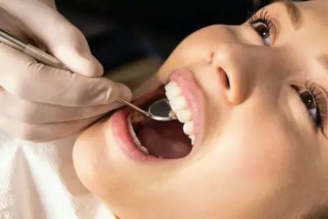Dentysta bada zęby pacjentki, przygotowując się do zabiegu gingiwektomii.