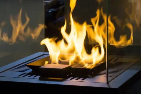 Flammen tanzen in einem modernen Kamin. Ein Pelletofen ohne Schornstein betreiben ist hier möglich, dank der Glasumrandung.