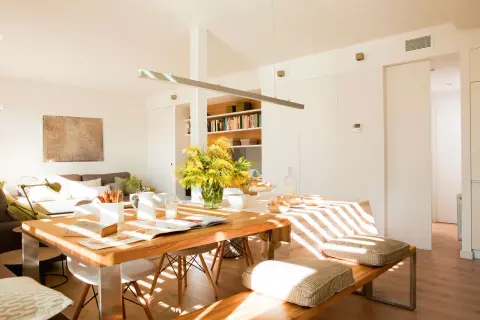 Un espacio luminoso y moderno para diseñar salón, con mesa de madera, sofás cómodos y estanterías llenas de libros.