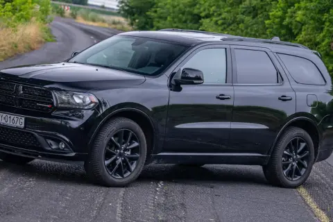 Czarny Dodge Durango 3.6 na krętej drodze, otoczony zielenią.