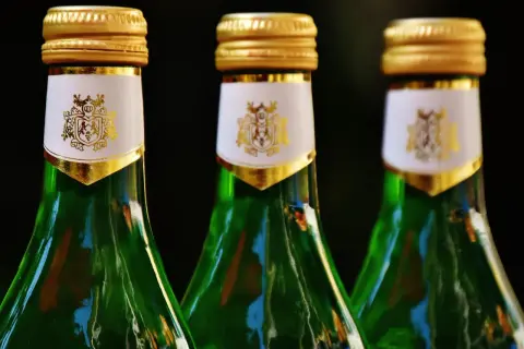 Trzy zielone butelki z złotymi nakrętkami i białymi etykietami z herbem. Czy to absynt? Co to jest?