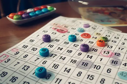 Kolorowe żetony bingo leżą na kartach do gry z zaznaczonymi liczbami.