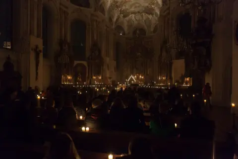 Menschen sitzen in einer dunklen Kirche, beleuchtet von Kerzen. Eine feierliche Vigil in der Kirche.
