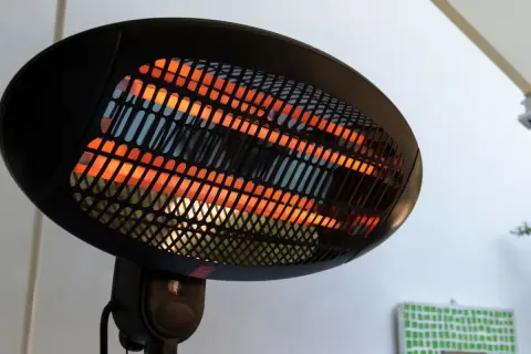 Lampada infrarossi terapia con elementi riscaldanti incandescenti arancioni dietro una griglia nera.