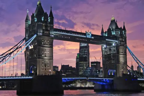 Wieczorny widok na Tower Bridge, jeden z najpiękniejszych zabytków w Londynie, z fioletowym niebem w tle.