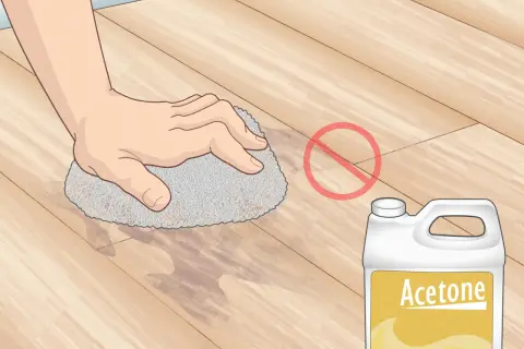 Main tenant, ne pas enlever peinture sur lino avec acétone. Une main frotte le sol avec une éponge.