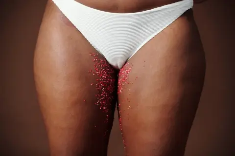 Féminité et saignement grossesse. Des paillettes rouges sur la peau, évoquant la fragilité et la vie.