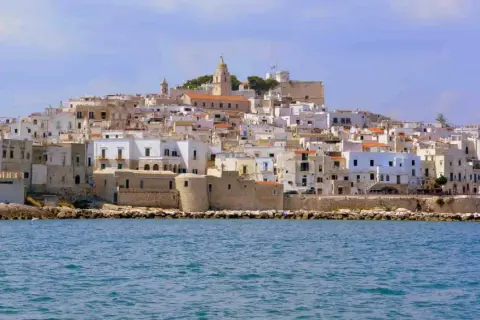 Un borgo bianco a picco sul mare, con un campanile in cima. Ricorda il vino primitivo, significato di sole e terra pugliese.