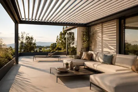 Terrazza con divano e lettino, sotto una pergola con lamelle orientabili, ideali come sistemi oscuranti esterni per finestre, con vista sul mare.