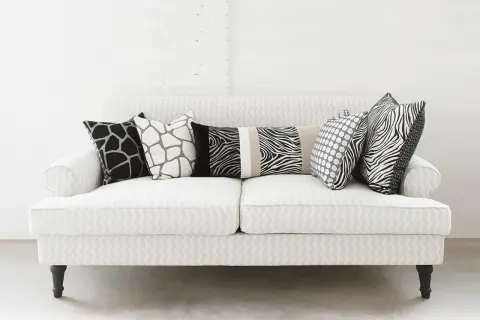 Un divano bianco con cuscini a fantasia animalier e pois: un'idea su come disporre i cuscini sul divano per un tocco moderno.